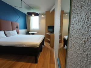a bedroom with a bed and a desk with a television at ibis Lyon Est Bron in Bron +24 photos