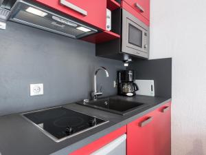 a kitchen with a sink and a microwave and red cabinets at Studio rénové à Tignes Le Lac, proche pistes et commerces, balcon et terrasse privative - FR-1-502-425 in Tignes