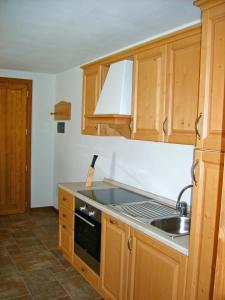 a kitchen with wooden cabinets and a sink at Pizzo Camino in Castione della Presolana