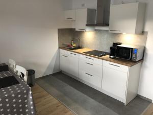 a small kitchen with white cabinets and a microwave at Ferienwohnung in Kaunitz bei Wessels in Verl