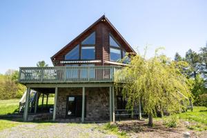 Una casa de troncos con un porche envolvente y un balcón. en 5BR Luxurious Mountain Escape, en Forksville