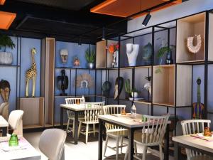 a restaurant with tables and chairs and vases on the wall at Ibis Styles Abidjan Plateau in Abidjan