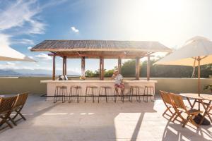 a man sitting at a bar on a patio at Hotel Waya Guajira By OxoHotel in Albania