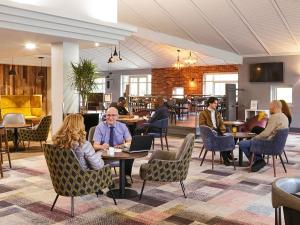 a group of people sitting at tables in a restaurant at Novotel Manchester West in Worsley