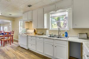a kitchen with white cabinets and a sink and a table at Fish and Explore Port Arthur Apt Near Sabine Lake! in Port Arthur