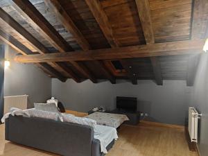 a bedroom with a couch and a tv and wooden ceilings at Aiestaenea Apartamentos Rurales in Isaba