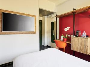 a room with a bed and a desk with a television at Ibis Milano Centro in Milan