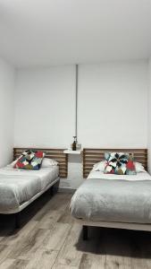 two beds in a bedroom with white walls and wooden floors at CASA GRANDE FINCA EL CALABRES in Agüimes