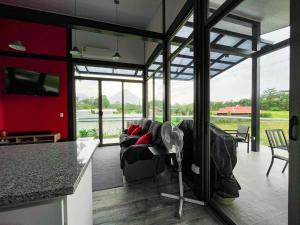 a living room with a couch and a kitchen with windows at Brisas del Volcán BnB in Fortuna +10 photos