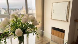 un jarrón de flores blancas sobre una mesa en una habitación en ASA | Premier Sunset | Piscina | Oktoberfest, en Blumenau 30 fotos más