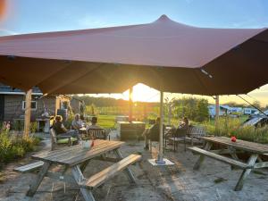 a group of people sitting at tables under a large umbrella at Erve Zonnehoeve B&B en Wijngaard in Vorden