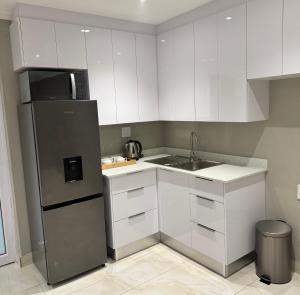 a kitchen with white cabinets and a stainless steel refrigerator at Luu Luxury Suite in East London