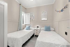 Dos camas en un dormitorio con paredes blancas y almohadas azules. en CASA playa 3dormitorios, en Málaga