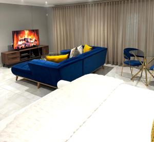 a living room with a blue couch and a tv at Luu Luxury Suite in East London