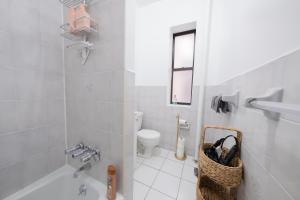 La salle de bains blanche est pourvue d'une baignoire et de toilettes. dans l'établissement Spacious 3BR Near Columbia Uni & Riverside Park, à New York 51 autres photos