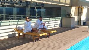 a man and woman sitting on a bench next to a pool at LUUM by Norus in Santiago