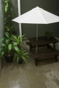 a picnic table with a white umbrella and potted plants at Casa Pousadinha Mel- QUARTOS E DORMITORIOS in Salvador