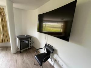 a black chair in a room with a television on the wall at Hotel Arupo Residence in Tababela