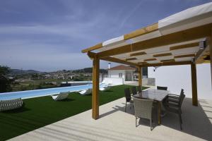 a patio with a table and chairs under a pavilion at Quinta da Bouça - Casa do Canastro in Vale de Cambra