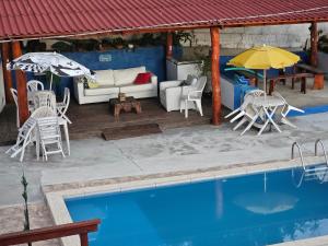 Un patio con piscina, sillas y sombrilla. en Hostel Yellow House MG, en Itamonte