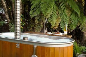 a hot tub in a garden with a palm tree at Hightide River Escape -with Outdoor Bath in Hokitika