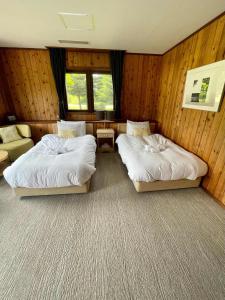 two beds in a room with wood paneled walls at The Lakehouse at Toyako - Vacation STAY 44251v in Tōya