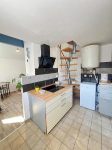 une cuisine avec des placards blancs et un escalier en colimaçon dans l'établissement Ty Glas des Abers, à Lannilis