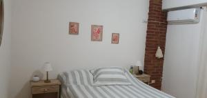 a bed in a white room with two night stands and two pictures at Departamento Urquiza2 in Alta Gracia