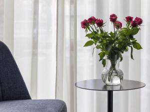 a vase of flowers on a table next to a chair at Mövenpick Zagreb in Zagreb