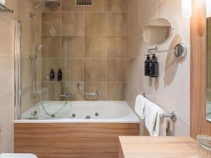 a bathroom with a tub with a shower and a mirror at Le Splendid Hotel Lac D'Annecy - Handwritten Collection in Annecy
