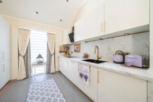 una cucina con mobili bianchi e un lavandino di Spacious 3 Bedroom Home with Terrace and Free Parking a Walferdange