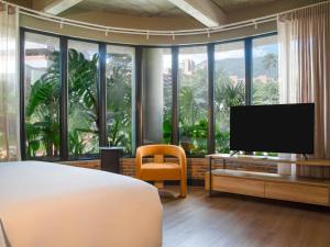 Un dormitorio con una cama y un televisor de pantalla plana. en Tribe Medellín, en Medellín