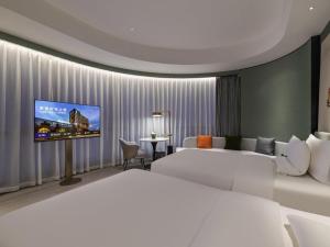 a hotel room with a bed and a flat screen tv at Novotel Shanghai Caohejing in Shanghai