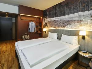 Un dormitorio con una gran cama blanca en una habitación. en Ibis Styles Singen, en Singen