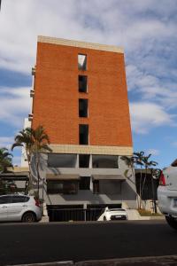 Un edificio de ladrillo con coches aparcados delante. en Maktub Hotel Itu, en Itu