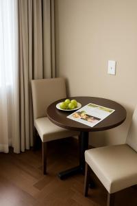 una mesa y una silla con un bol de fruta. en Suite Confort - Resort em Gramado, en Gramado
