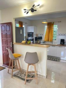 a kitchen with a counter and two stools in it at Soleil éclatant in Sainte-Anne