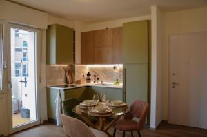 a kitchen with a table and chairs and a kitchen with green cabinets at Apartment-alys in Pordenone