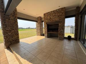 a patio with a stone fireplace in a house at Fairway Escape in Grooteiland