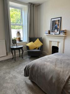 a bedroom with a bed and a chair and a fireplace at Large Mach Apartment at Pen Y Coed Hall in Dolgellau