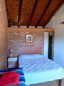 un lit dans une chambre avec un mur de briques dans l'établissement La Serranita, à Panaholma