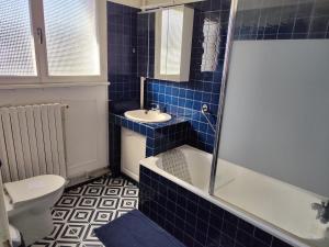 a blue tiled bathroom with a toilet and a sink at Maison 3 chambres Le Mans, proche circuit in Le Mans