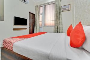a bedroom with a bed with red pillows and a television at HOTEL O THE ROYAL INN in Jaipur +20 photos
