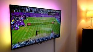 a flat screen tv hanging on a wall with a tennis game at Superb Guest Room in London