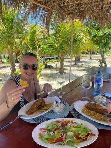 a woman sitting at a table with plates of food at Tubazenika Paradise Lodge - San blas in Tupile