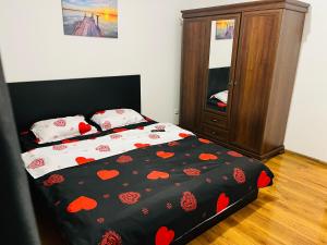a bedroom with a bed with a black comforter with red hearts at Apartament Soseaua Stefan cel mare in Bucharest