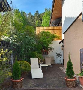 a patio with two white chairs and a table at Beas Ferienglück in Busenberg