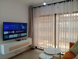 a living room with a flat screen tv and a table at 3 bdr apartment with Solar Backup & Wi-Fi Salama in Lusaka