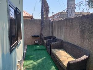 a patio with two wicker chairs and a green floor at 3 bdr apartment with Solar Backup & Wi-Fi Salama in Lusaka