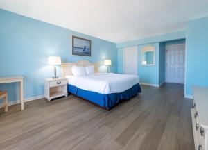 1 dormitorio con 1 cama con paredes azules y suelo de madera en Drifting Sands Oceanfront Hotel, en Ship Bottom